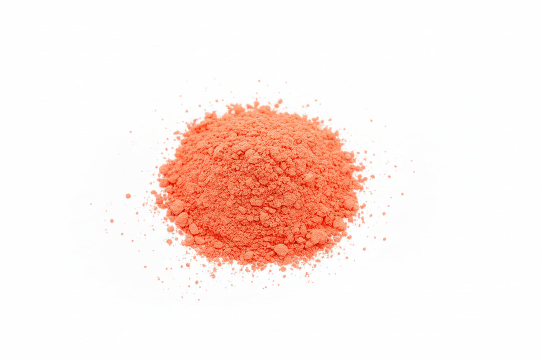 A small pile of bright orange-red powder on a light blue background.