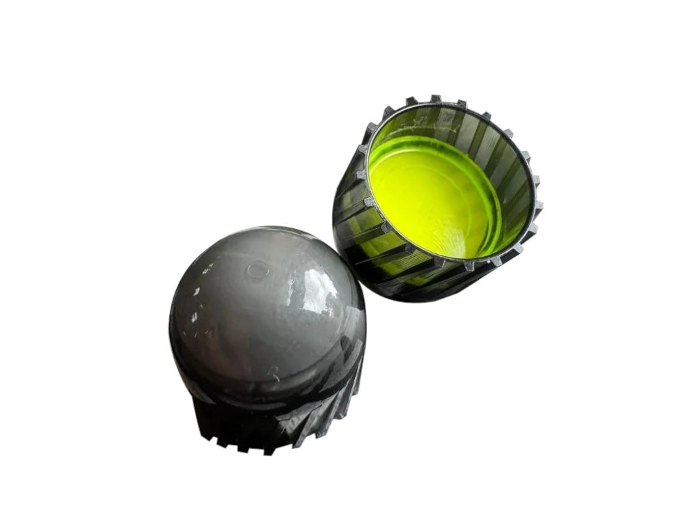 Two small plastic components on a plain white background: a dark gray rounded cap-like piece and a ribbed black cup-like piece with a bright yellow-green interior.