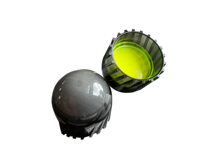 Two small plastic components on a plain white background: a dark gray rounded cap-like piece and a ribbed black cup-like piece with a bright yellow-green interior.